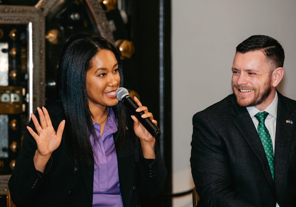 Two panelists sharing a microphone, one gesturing, both laughing.