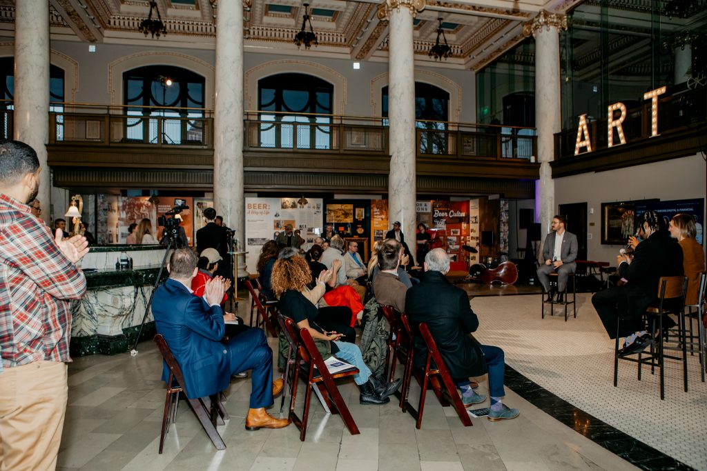Attendees seated in rows across the marble hall beneath the ART MKE sign.