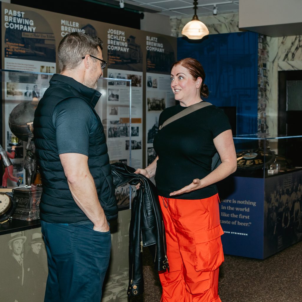 Two attendees talking beside a Pabst Brewing Company exhibit panel in the museum.