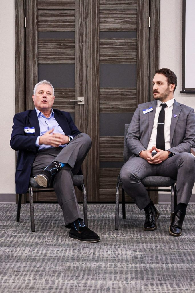 Two speakers seated for a fireside-style conversation at the front of the room.
