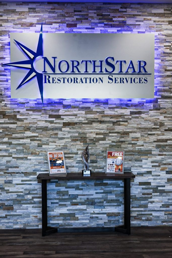 The NorthStar Restoration Services sign above the venue's welcome table, set with printed materials.